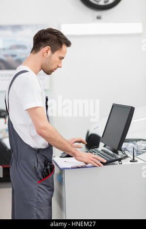 Vista laterale della meccanica automobilistica utilizzando computer in officina Foto Stock