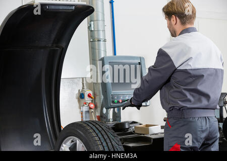 Vista posteriore della metà degli adulti meccanico di automobile il lavoro in officina Foto Stock