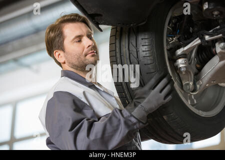 Metà tecnico adulto regolazione auto del pneumatico in officina Foto Stock