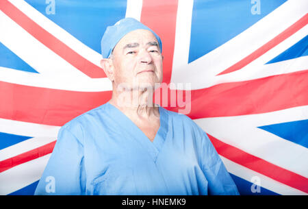 Ritratto di un adulto Senior chirurgo davanti a una bandiera britannica Foto Stock