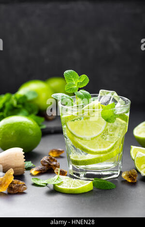 Estate menta lime rinfrescante cocktail mojito con il rum e il ghiaccio in vetro su sfondo nero in vista superiore Foto Stock