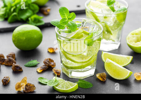 Estate menta lime rinfrescante cocktail mojito con il rum e il ghiaccio in vetro su sfondo nero in vista superiore Foto Stock