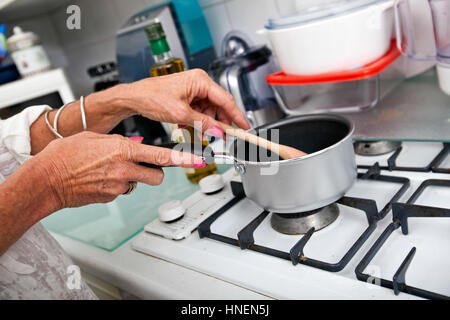 Immagine ritagliata della donna senior per la cottura in cucina Foto Stock