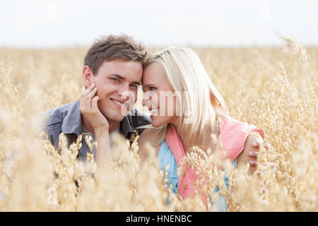 Ritratto di felice uomo seduto con una romantica donna in mezzo al campo Foto Stock