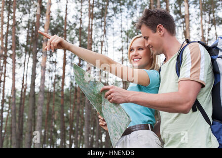 Felice giovani escursionismo giovane azienda mappa con donna rivolto lontano nella foresta Foto Stock