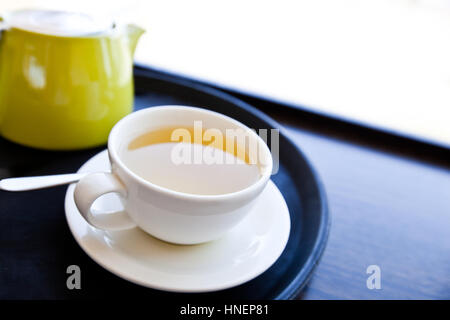 Tazza di tè verde su un vassoio con un piattino e cucchiaio Foto Stock