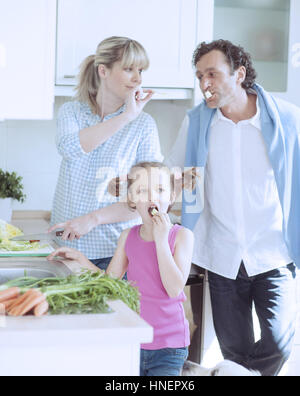 Famiglia facendo una sana insalata in cucina Foto Stock