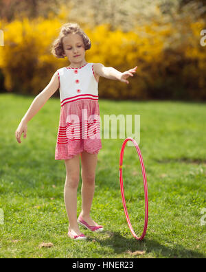 Ragazza giovane rolling hula hoop in posizione di parcheggio Foto Stock