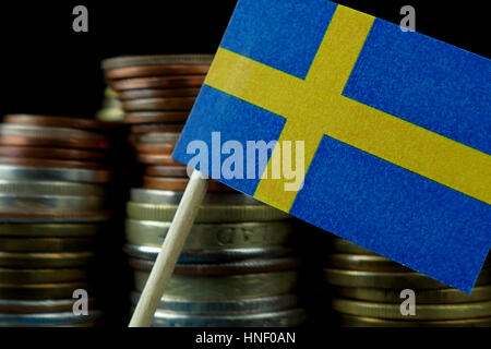 Bandiera della Svezia che ondeggia con pila di denaro monete macro Foto Stock