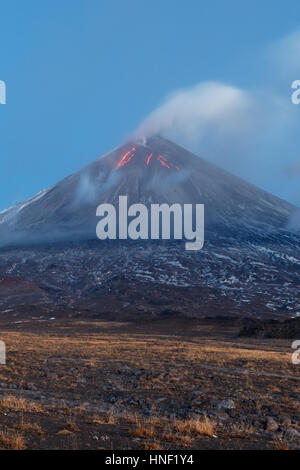 Paesaggio vulcanico della penisola di Kamchatka: eruzione del vulcano Klyuchevskoy, flussi di lava sul pendio del vulcano; pennacchio di gas, vapore di cenere dal cratere. Foto Stock