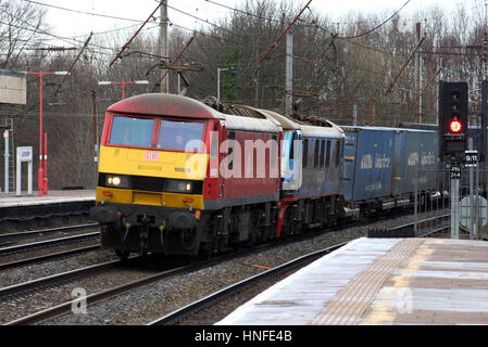 Classe 90 locomotive elettriche con un contenitore treno passa attraverso Lancaster stazione sulla linea principale della costa occidentale di lunedì 6 febbraio 2017 Foto Stock