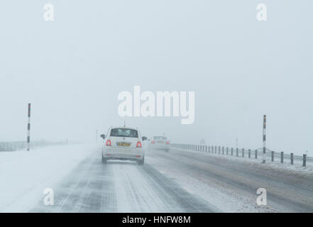 Bianco auto la guida su una strada66 in Inghilterra settentrionale in inverno in tempesta di neve Foto Stock