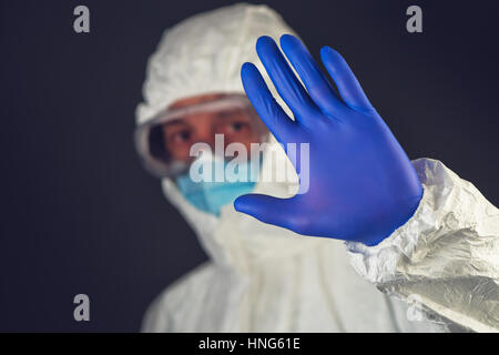 Scienziato medico di indossare abbigliamento protettivo e vetreria gesticolando segno di stop in quarantena Foto Stock