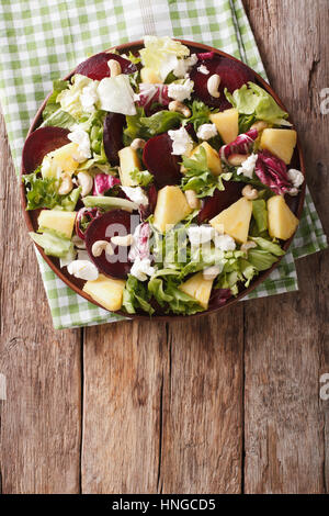 Cibo sano: insalata di bietole, ananas, formaggio di capra e verdi mix closeup su una piastra verticale di vista da sopra Foto Stock