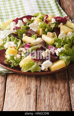 Gustosa insalata di bietole, ananas, crema di formaggio, anacardi e verdi closeup su di una piastra verticale. Foto Stock