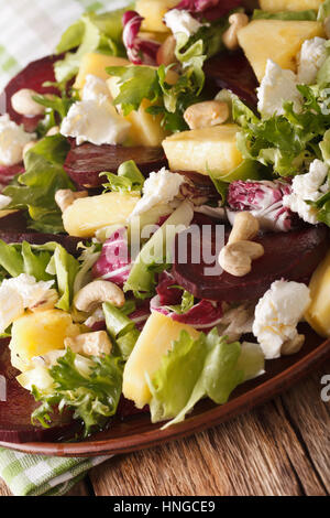 Cibo sano: insalata di bietole, ananas, formaggio di capra e verdi mix closeup su di una piastra verticale. Foto Stock