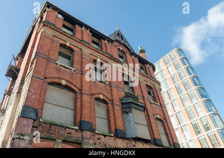 Abbandonato edificio vittoriano con imbarcati su windows e moderno edificio dietro di esso in Birmingham Foto Stock