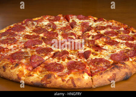 Intere fette di salsiccia per pizza pizza servita sul ciliegio scuro di impiallacciatura di legno tabella Foto Stock