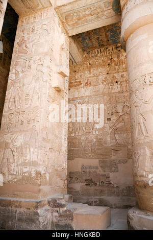 Dipinti egiziani, carving figure e geroglifici in colonne e una parete di pietra miliare tempio di Ramses o Ramesse III a Medinet Habu, monumento in Luxo Foto Stock