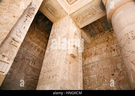 Dipinti egiziani, carving figure e geroglifici in colonne e una parete di pietra miliare tempio di Ramses o Ramesse III a Medinet Habu, monumento in Luxo Foto Stock