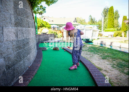 Ragazza giovane a giocare a mini-golf o crazy golf presso il campo da mini-golf in estate Foto Stock