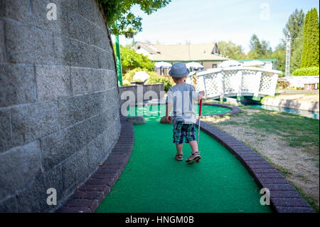 Little Boy preschooler giocare a mini-golf o crazy golf presso il campo da mini-golf in estate Foto Stock