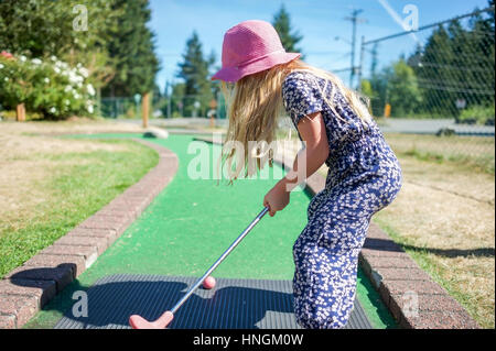 Ragazza giovane a giocare a mini-golf o crazy golf presso il campo da mini-golf in estate Foto Stock