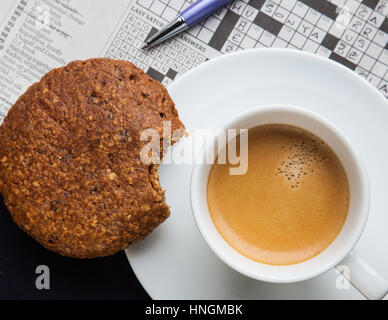 Espresso con una sana cookie e un cruciverba Foto Stock