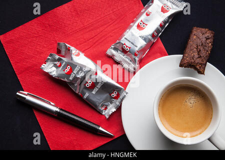 Caffè espresso con una penna e snack sani su un tovagliolo rosso Foto Stock