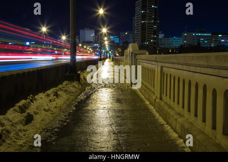 Un marciapiede bagnato di notte tempo. Foto Stock