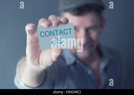 Uomo con in mano una carta con le parole Contattaci Foto Stock