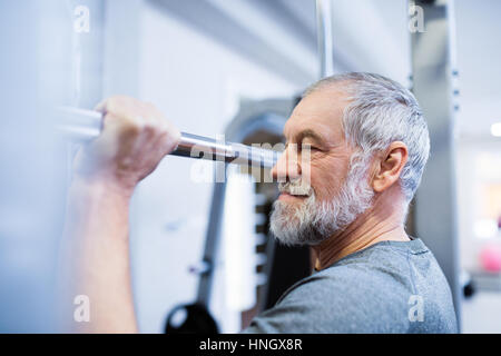 Uomo Senior in palestra facendo pull-ups sulla barra orizzontale. Foto Stock