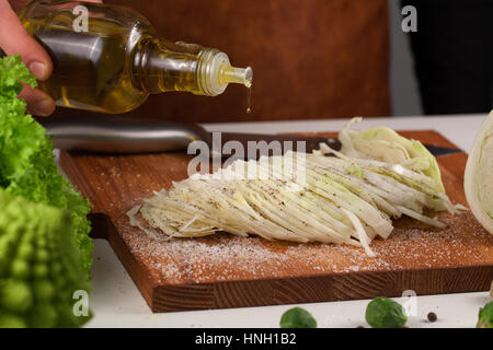 Vista ravvicinata oh mano dello chef versando olio d'oliva da una bottiglia di vetro. Uno stile di vita sano e dieta concetto Foto Stock