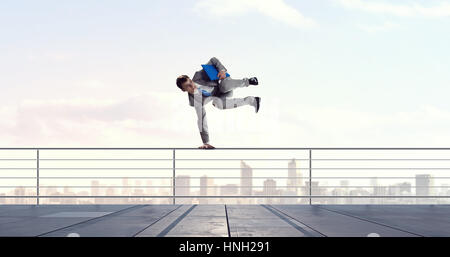 Giovane imprenditore allegro facendo handstand su parapetto Foto Stock