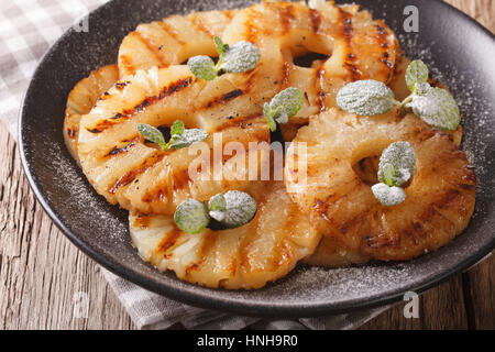 Deliziose grigliate di ananas con la menta vicino su una piastra sul tavolo orizzontale. Foto Stock