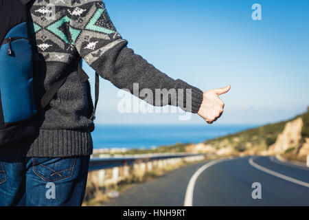 Viaggio, viaggio, gesto e concetto di persone - hitchhiker arresto auto con pollice in alto segno a mano Foto Stock