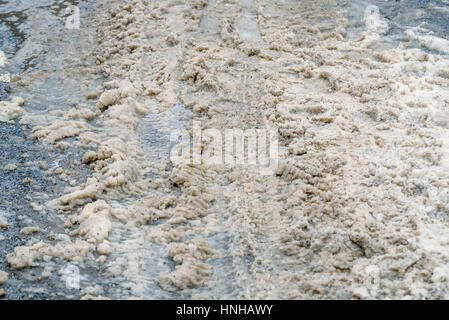 Neve e granite impronte sulla strada in inverno Foto Stock