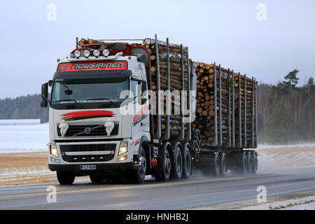 SALO, Finlandia - 20 gennaio 2017: il bianco e il rosso Volvo FH combinazione veicolo di Kuljetusliike E Nousiainen trasporta pasta legno lungo l'autostrada bagnata con Foto Stock