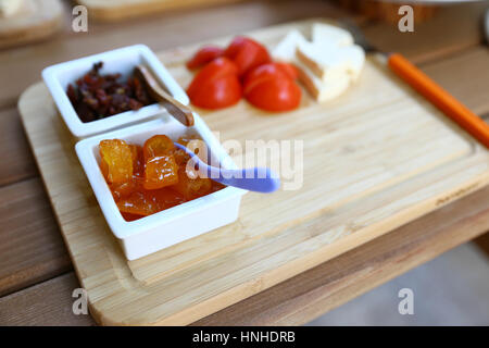 Vista ingrandita della colazione in legno piastra con marmellata, formaggio e pomodoro, copia dello spazio. Foto Stock