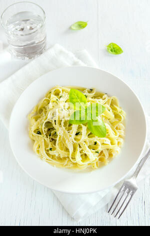 Tagliatelle al pesto, il formaggio e le foglie di basilico sulla piastra bianca - una sana pasta fatta in casa Foto Stock