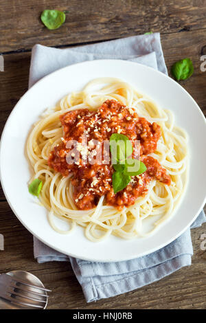 Spaghetti alla bolognese la pasta con la salsa di pomodoro e carne macinata, parmigiano grattugiato e basilico fresco - le sane italiano sulla pasta di legno rustico Foto Stock