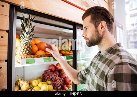 Attraente giovane acquisto di frutta fresca in un negozio di generi alimentari Foto Stock