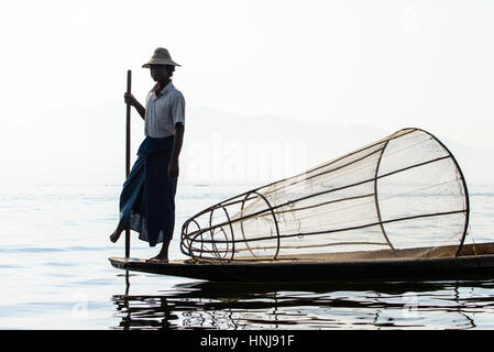Lago Inle, MYANMAR - 15 febbraio 2014: pescatore birmano sulla barca di bambù per la cattura di pesce in modo tradizionale con la rete a mano. Lago Inle, Myanmar (Birmania Foto Stock