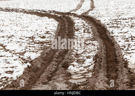 Strada sterrata che passa attraverso il settore agricolo. Auto tracce lasciate sul terreno. Stagione invernale. La foto è stata scattata da vicino da cima a fondo. Piccolo dep Foto Stock