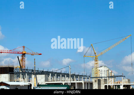 Alta gru durante la costruzione di un nuovo centro commerciale. sullo sfondo cielo blu con nuvole Foto Stock