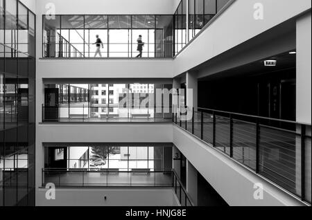 Moderno edificio pubblico interno con due figure a piedi in background. Alto contrasto immagine in bianco e nero Foto Stock