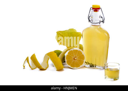 Aprire il vetro della bottiglia del decantatore e colpo di vetro riempito con il colore giallo limone o liquore limoncello o limoncino sul bianco. Sbucciate organico naturale di limone. Foto Stock