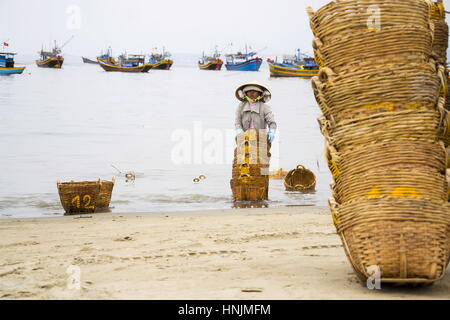 MUI NE, VIETNAM - febbraio 7: Donna di cestelli di lavaggio per le acciughe utilizzato per la salsa di pesce il 7 febbraio 2012 in Mui Ne, Vietnam. Foto Stock