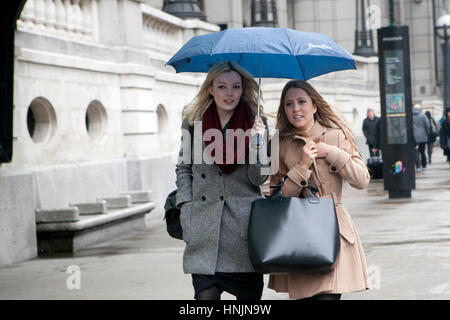 LONDON, Regno Unito - 22 Aprile 2016: Due ragazze sotto un ombrello in un giorno di pioggia attraversare la strada Foto Stock