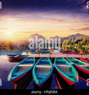 Barca sul dock circondato montagne, cielo stellato . Fantastico Sh Foto Stock